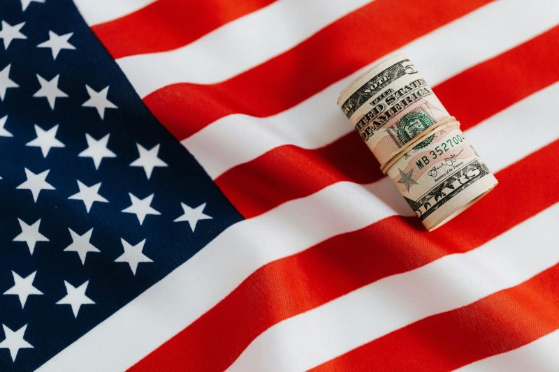 United States currency rolled up on an American flag, symbolizing business profit and wealth.