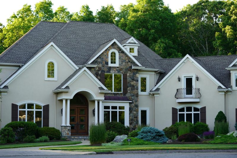 A large suburban house surrounded by vibrant greenery and trees.