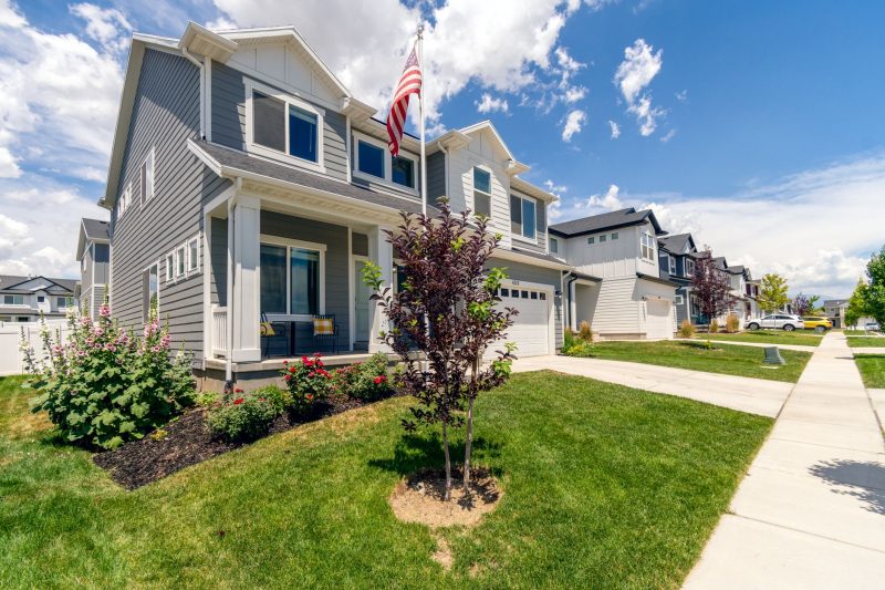 Modern suburban house with a well-kept garden and an American flag, featuring elegant architecture.