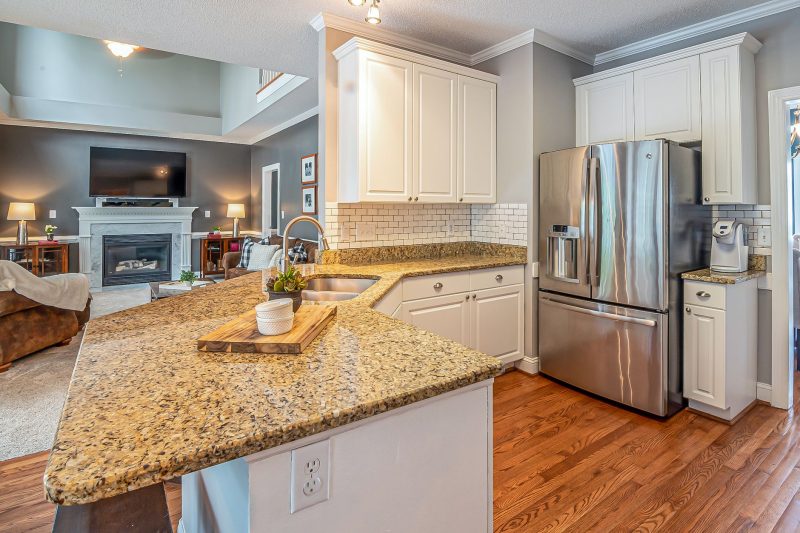 Luxurious open-concept kitchen with granite countertops and modern appliances, transitioning into a cozy living room with a fireplace.