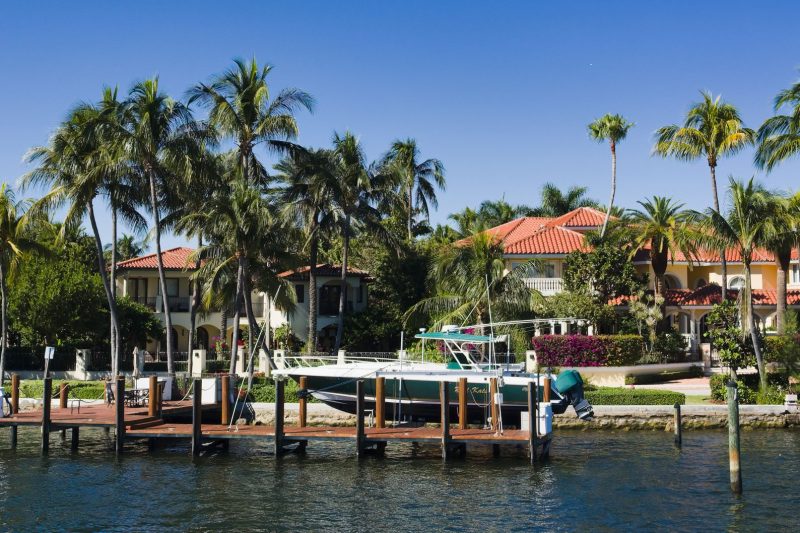 Luxury waterfront homes lined with palm trees and a boat docked in Fort Lauderdale, Florida.