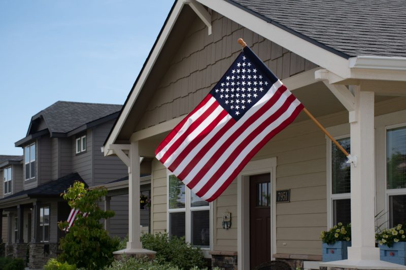 Vibrant American flag displayed outside a stylish suburban house on a bright, clear day.