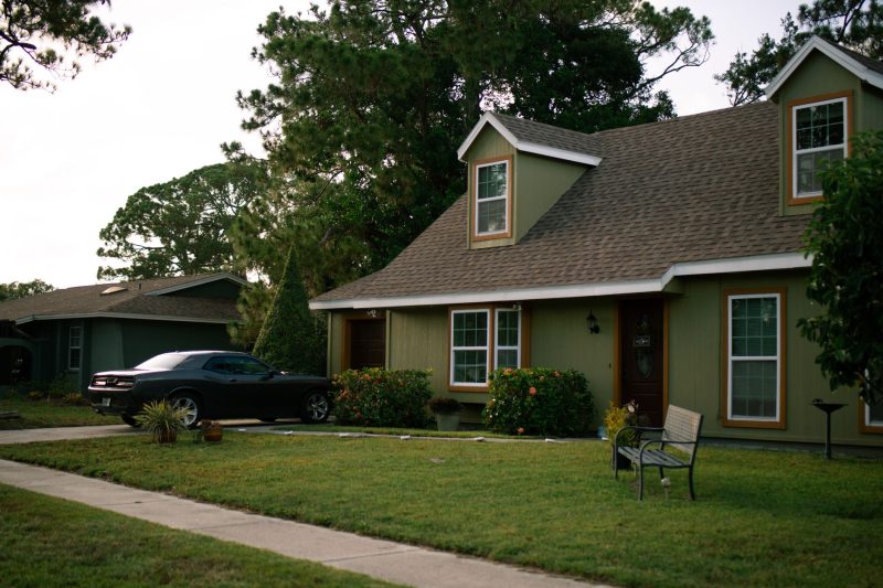 Suburban home with a well-maintained green lawn and parked car, showcasing residential comfort.